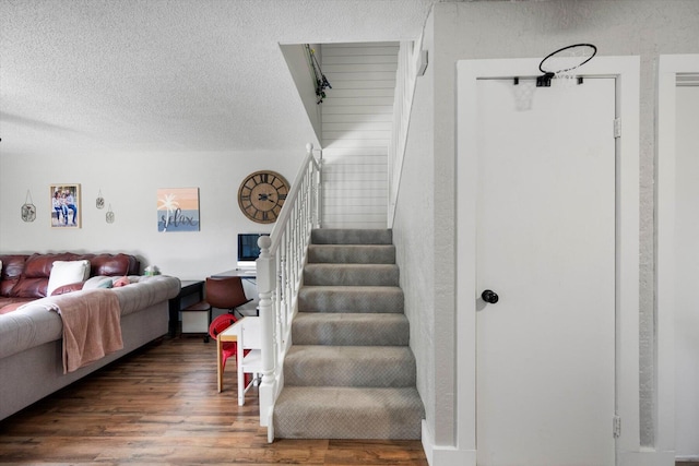 staircase with a textured ceiling and hardwood / wood-style floors