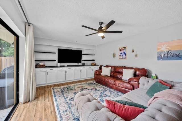 living room with a textured ceiling, ceiling fan, and light wood-type flooring