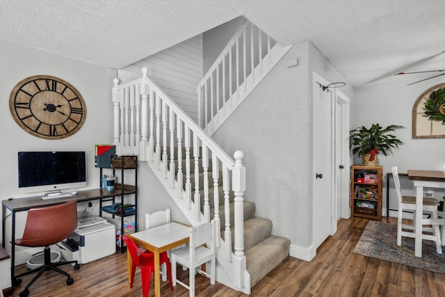 staircase featuring a textured ceiling, hardwood / wood-style floors, and ceiling fan