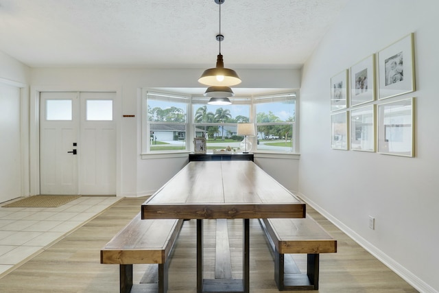 unfurnished dining area featuring light tile patterned flooring, a textured ceiling, and baseboards