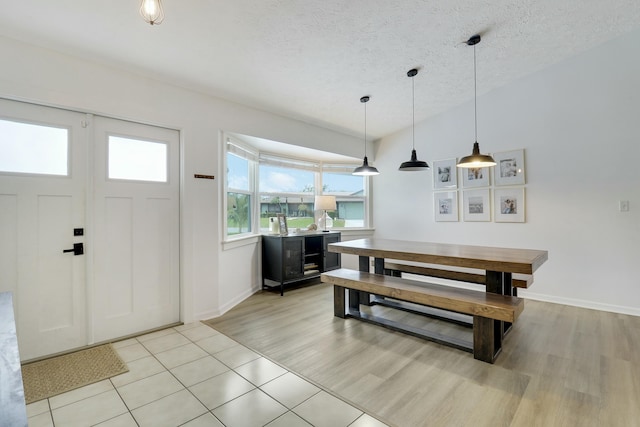 dining room featuring light wood finished floors, baseboards, and a textured ceiling