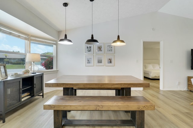 dining area featuring light wood-style floors, vaulted ceiling, and baseboards