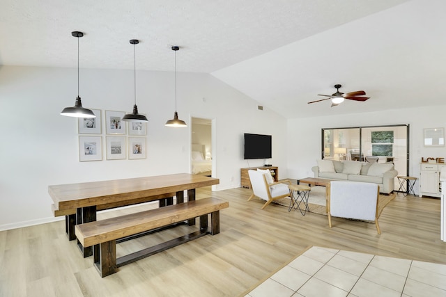 dining room featuring light wood finished floors, ceiling fan, baseboards, and vaulted ceiling