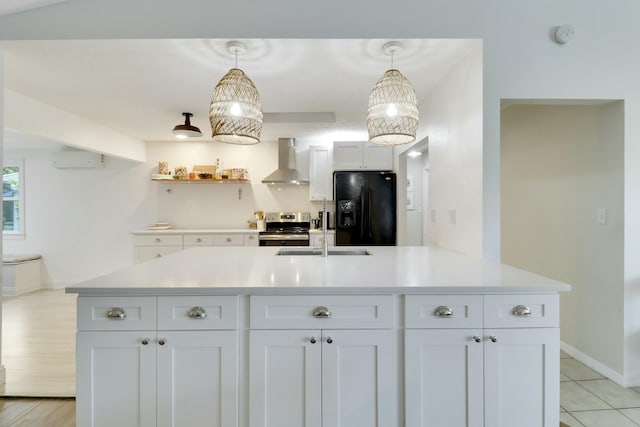 kitchen featuring stainless steel electric stove, an AC wall unit, a sink, wall chimney exhaust hood, and black fridge