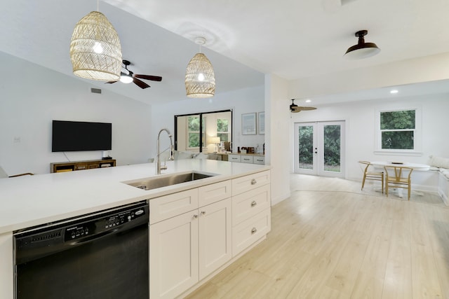 kitchen featuring black dishwasher, light wood-style flooring, open floor plan, light countertops, and a sink