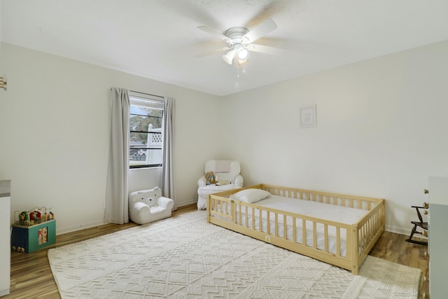 bedroom featuring ceiling fan, baseboards, and wood finished floors