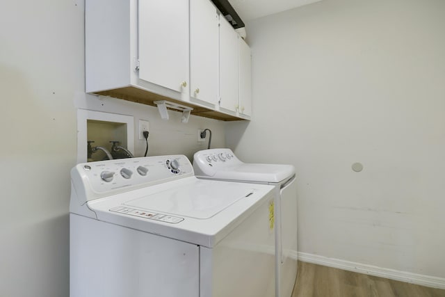 clothes washing area featuring light wood-style flooring, washing machine and clothes dryer, cabinet space, and baseboards