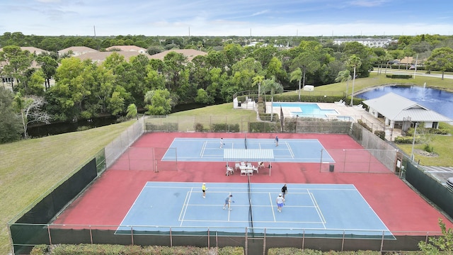 view of tennis court with a lawn and fence