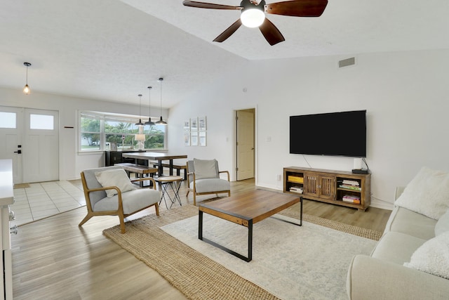 living room with vaulted ceiling, light wood finished floors, visible vents, and a ceiling fan