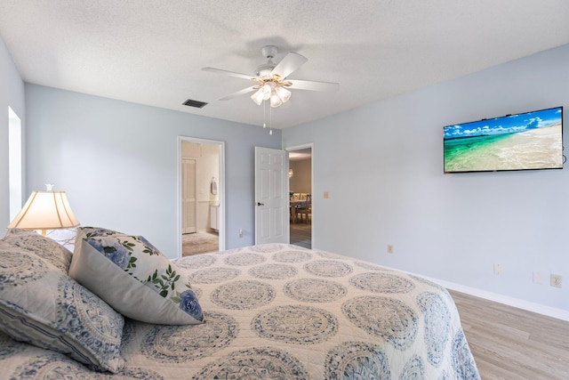 bedroom with connected bathroom, a textured ceiling, ceiling fan, and light wood-type flooring