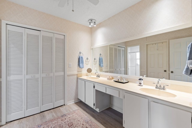 bathroom with ceiling fan, a textured ceiling, vanity, and wood-type flooring