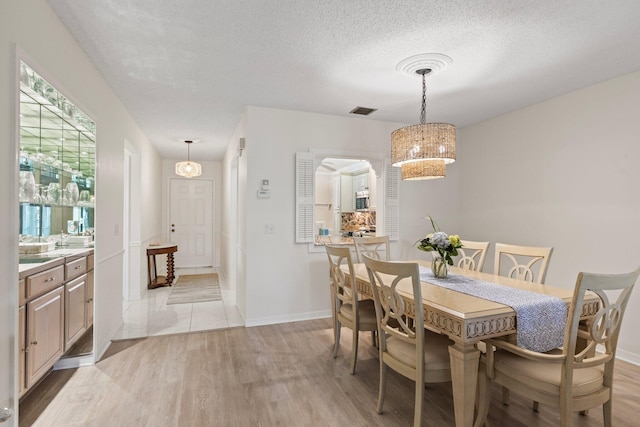 dining area with a textured ceiling and light hardwood / wood-style flooring