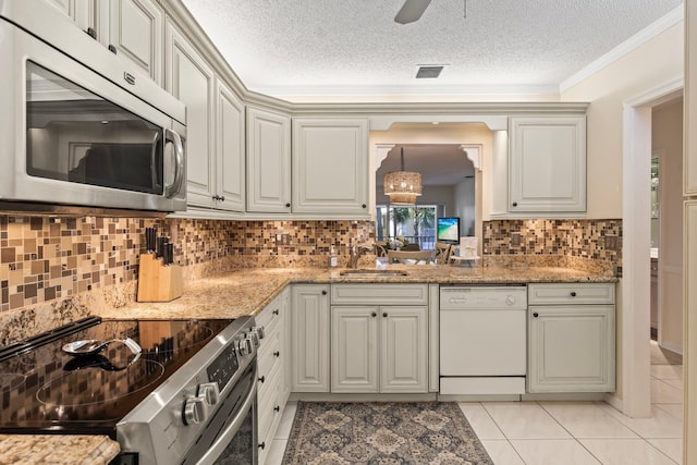 kitchen featuring stainless steel appliances, a textured ceiling, sink, and light stone counters