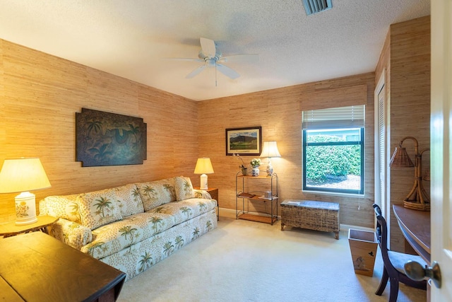 living room with ceiling fan, carpet flooring, and a textured ceiling