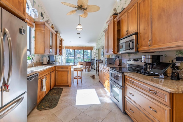 kitchen with pendant lighting, sink, appliances with stainless steel finishes, light stone counters, and light tile patterned flooring