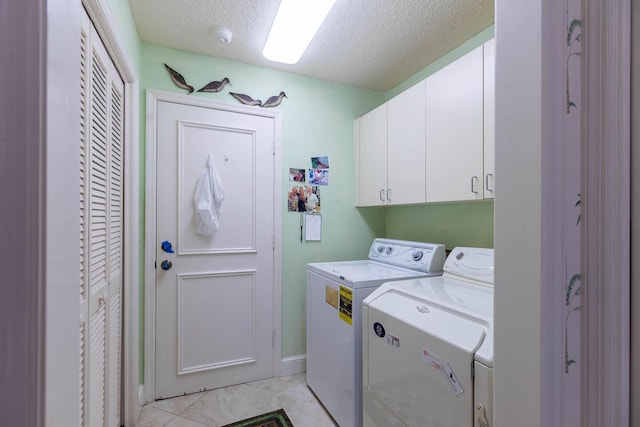 clothes washing area with a textured ceiling, cabinets, and washing machine and clothes dryer