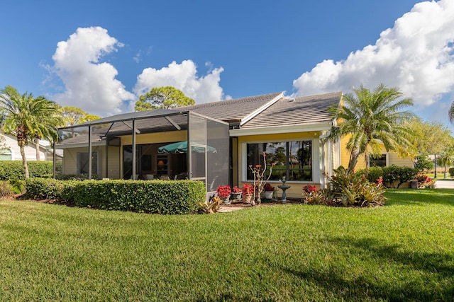 back of property featuring a lanai and a lawn