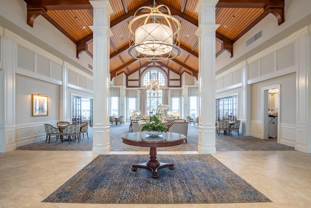 tiled foyer entrance with wooden ceiling, a wealth of natural light, decorative columns, and a notable chandelier