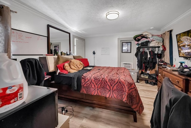 bedroom with light hardwood / wood-style flooring, ornamental molding, a closet, and a textured ceiling