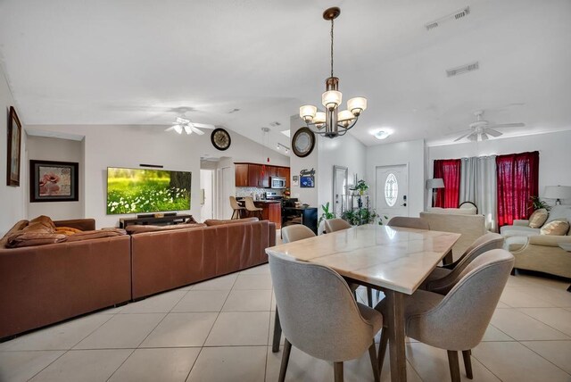 dining room featuring ceiling fan with notable chandelier, vaulted ceiling, and light tile patterned flooring