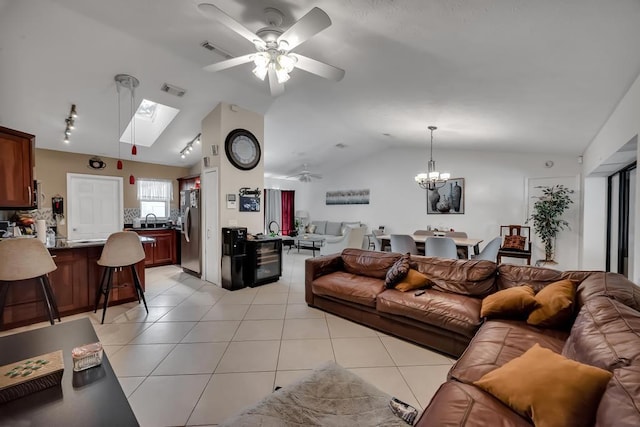 tiled living room with lofted ceiling with skylight and ceiling fan with notable chandelier