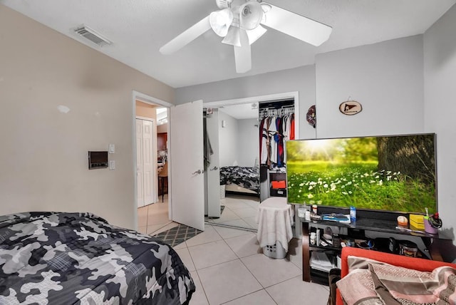 tiled bedroom with ceiling fan and a closet