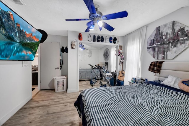 bedroom with ceiling fan, light hardwood / wood-style floors, and a textured ceiling