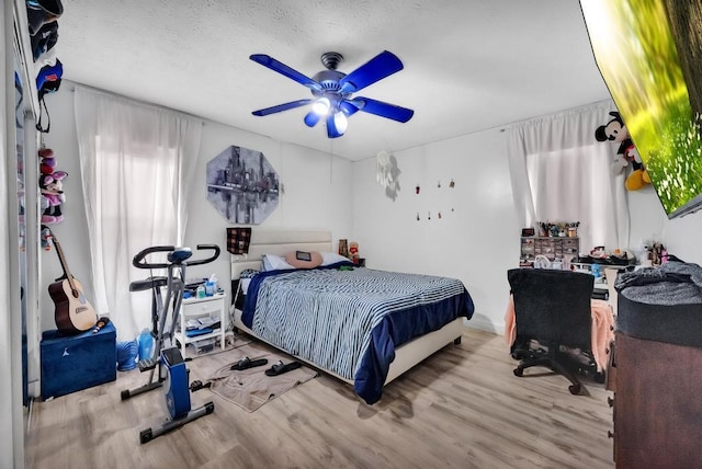 bedroom with ceiling fan, a textured ceiling, and light wood-type flooring