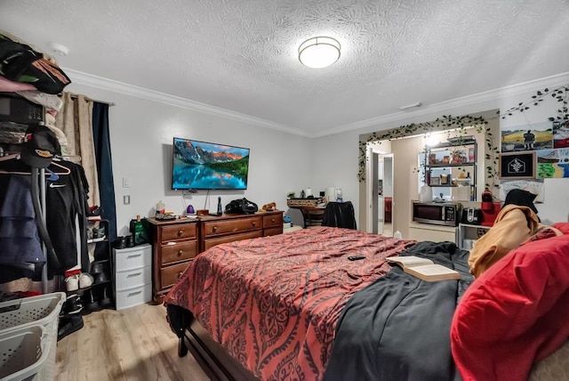 bedroom featuring light hardwood / wood-style flooring, ornamental molding, and a textured ceiling