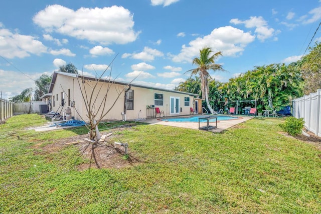 rear view of property featuring a yard, a fenced in pool, and central air condition unit