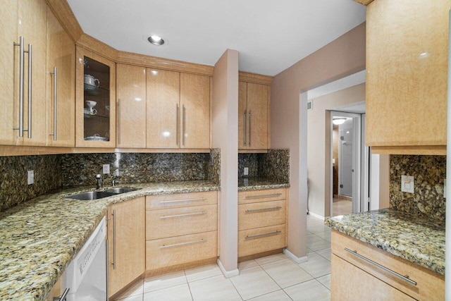 kitchen featuring white dishwasher, backsplash, light stone counters, and sink