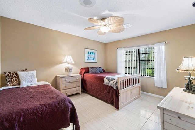 bedroom featuring ceiling fan, a textured ceiling, and light tile patterned floors