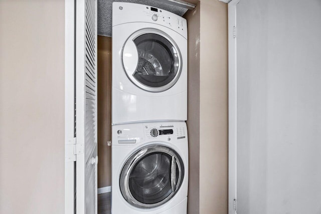 clothes washing area featuring a textured ceiling and stacked washer and clothes dryer