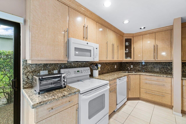 kitchen featuring white appliances, stone counters, light tile patterned floors, light brown cabinetry, and sink