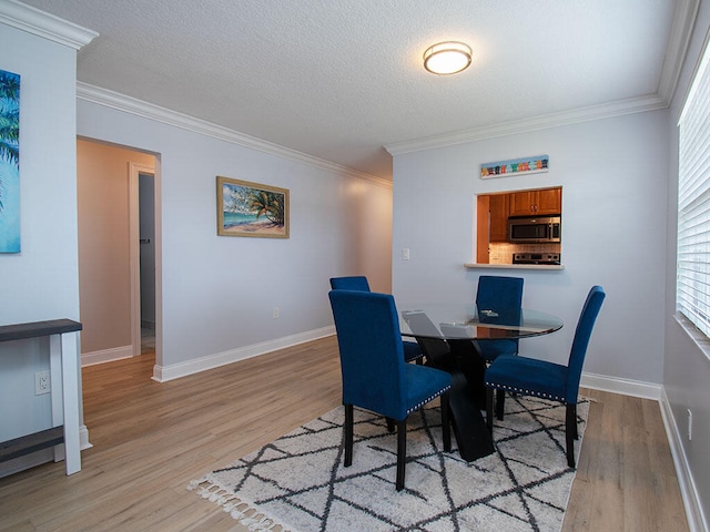 dining space with crown molding, light wood-style flooring, and baseboards