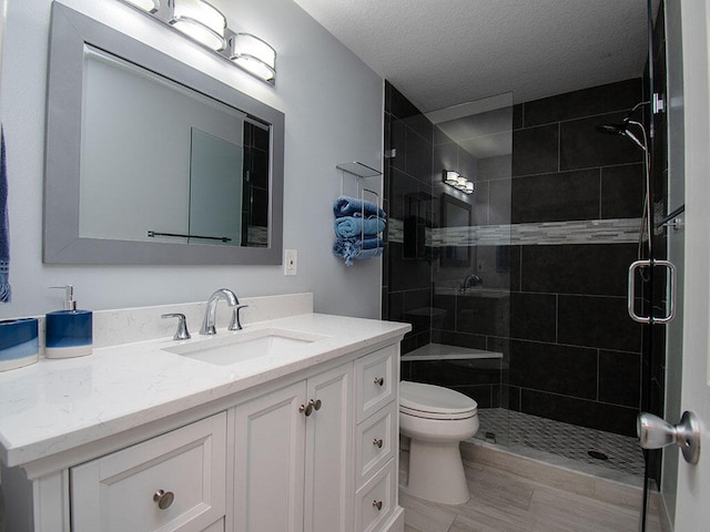 full bath featuring a textured ceiling, a shower stall, toilet, and vanity