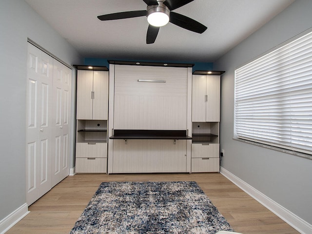 interior space featuring light wood-type flooring, baseboards, and a ceiling fan