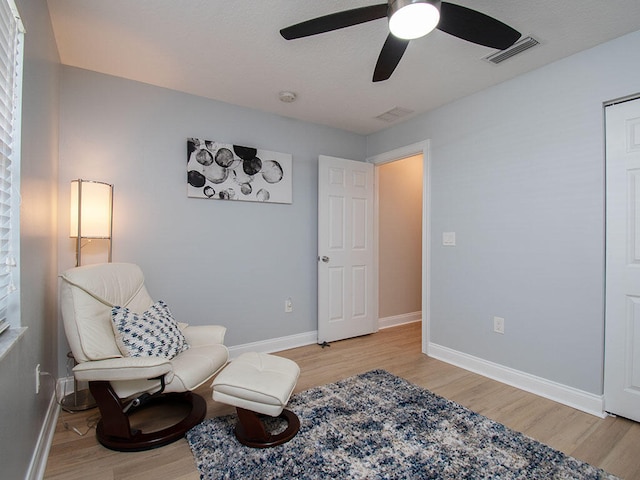 sitting room featuring a ceiling fan, baseboards, visible vents, and light wood finished floors