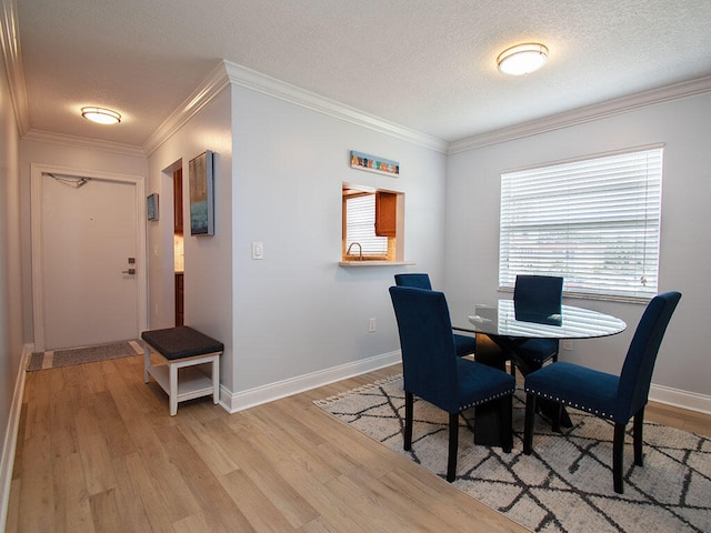 dining area featuring crown molding, a textured ceiling, and light wood-style floors