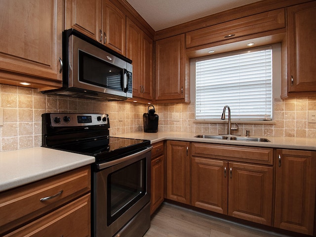 kitchen featuring a sink, light countertops, appliances with stainless steel finishes, backsplash, and brown cabinets