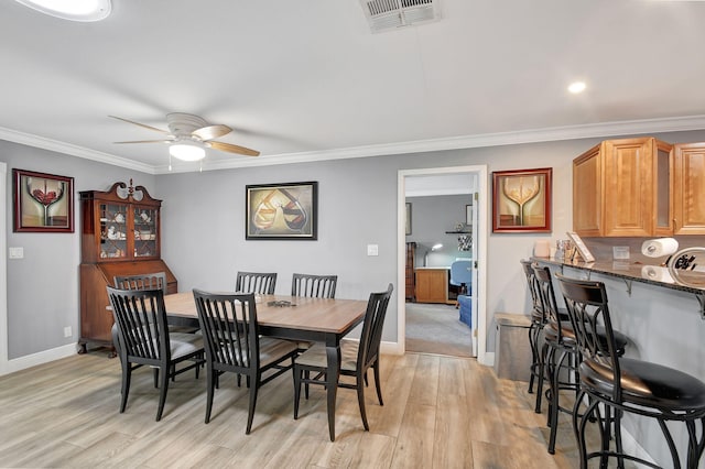 dining area with ceiling fan, crown molding, and light wood-type flooring