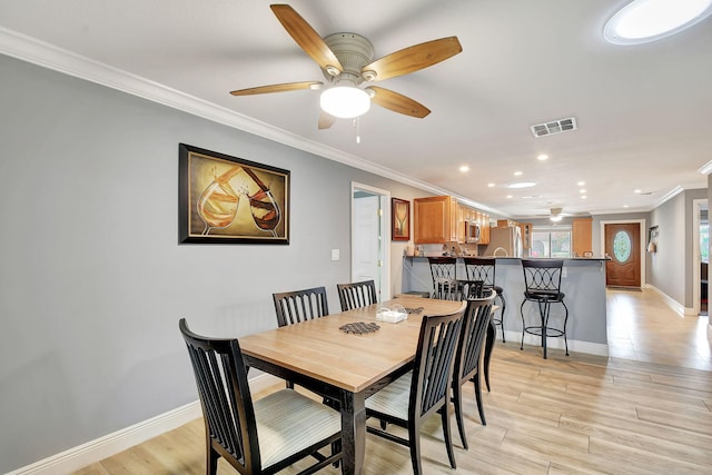 dining space with ceiling fan, crown molding, and light hardwood / wood-style flooring