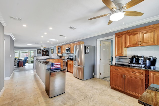 kitchen featuring crown molding, appliances with stainless steel finishes, dark stone countertops, and decorative backsplash