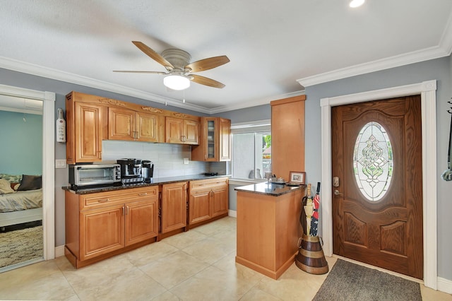 kitchen featuring ceiling fan, backsplash, light tile patterned flooring, dark stone countertops, and ornamental molding