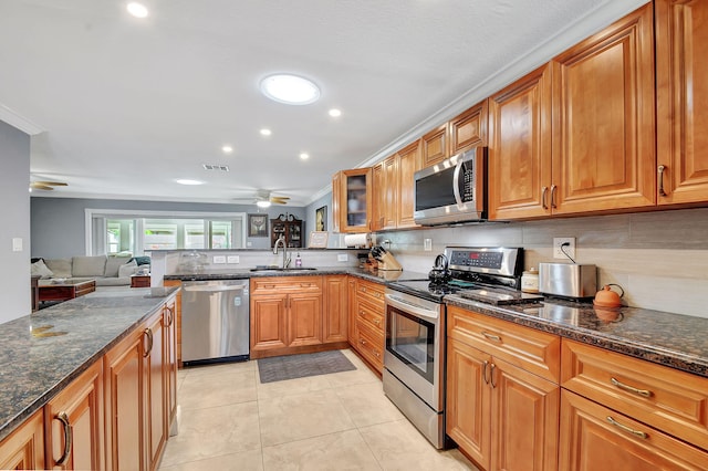 kitchen featuring appliances with stainless steel finishes, dark stone countertops, sink, light tile patterned flooring, and ceiling fan