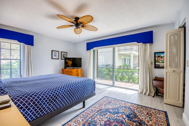 bedroom featuring multiple windows, a textured ceiling, access to outside, and ceiling fan