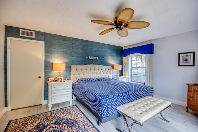 bedroom with ceiling fan, a textured ceiling, and light hardwood / wood-style flooring