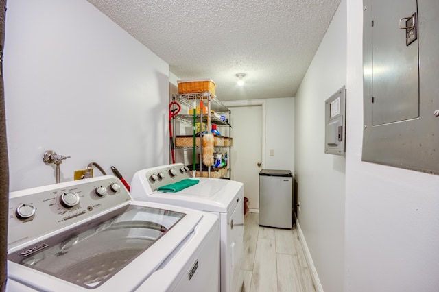 laundry room with electric panel, washer and clothes dryer, light hardwood / wood-style floors, and a textured ceiling