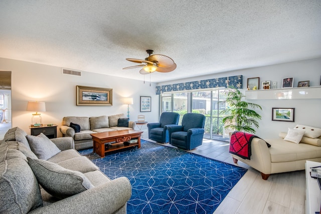 living room with ceiling fan, wood-type flooring, and a textured ceiling