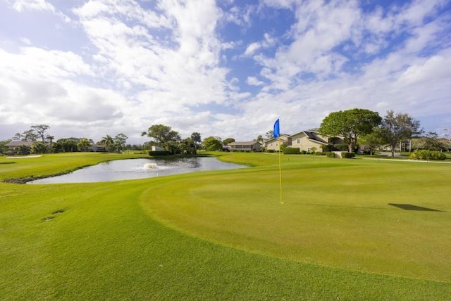 surrounding community with a water view and a lawn